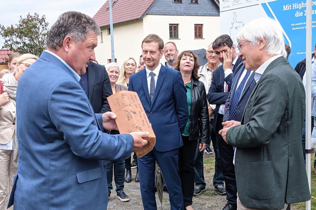 GLASFASER - Spatenstich Breitbandausbau 5 Uwe Geißler (Geschäftsführer der KÖNIG Elektro Fernmeldebau GmbH) überreicht Dr. Norbert Vornehm (Geschäftsführer der Wurzener Land-Werke Glasfaser GmbH) symbolisch ein Kabelschutzrohr mit Unterschriften