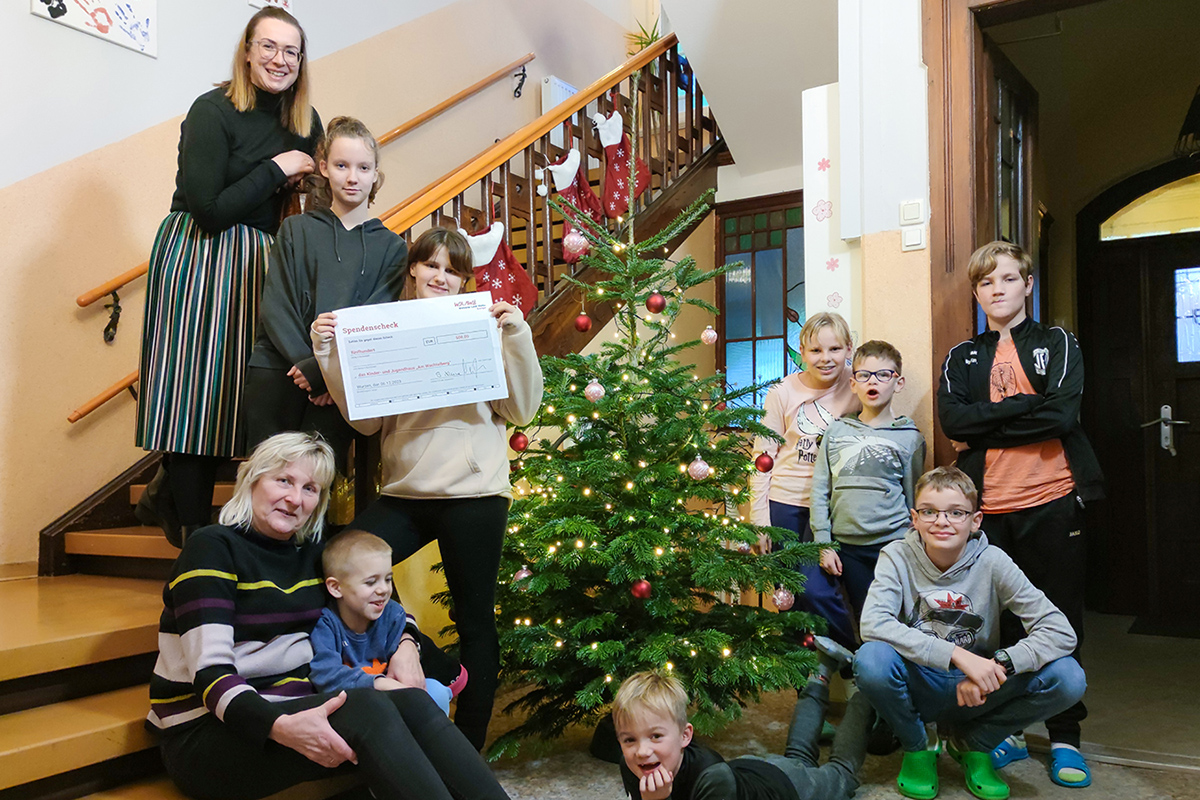 Die Kinder des Kinder- und Jugendhauses „Am Wachtelberg“ mit Einrichtungsleiterin Martina Jüntschke und Geschäftsführerin Stefanie Kleine am Weihnachtsbaum