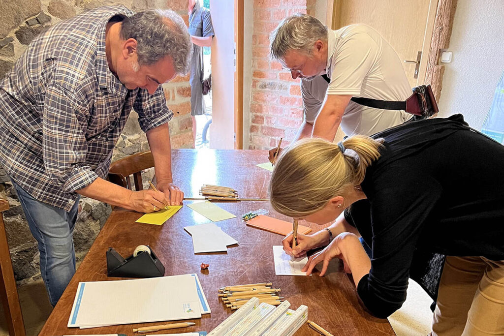 HOLDING - 1. und 2. Bürgerdialog Thallwitz 3 Eine Bürgerin und zwei Bürger füllen schreiben ihre Anmerkungen auf einen Zettel