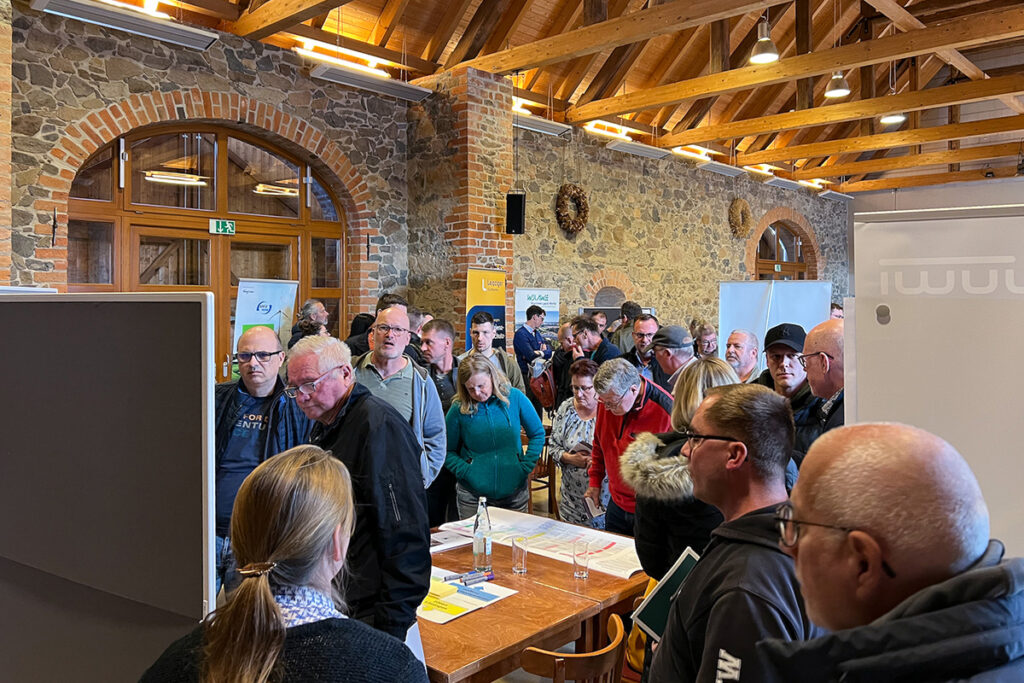 HOLDING - 4. Bürgerdialog Thallwitz 4 Eine Menschengruppe versammelt sich an einem Infostand im KulturGUT Thallwitz