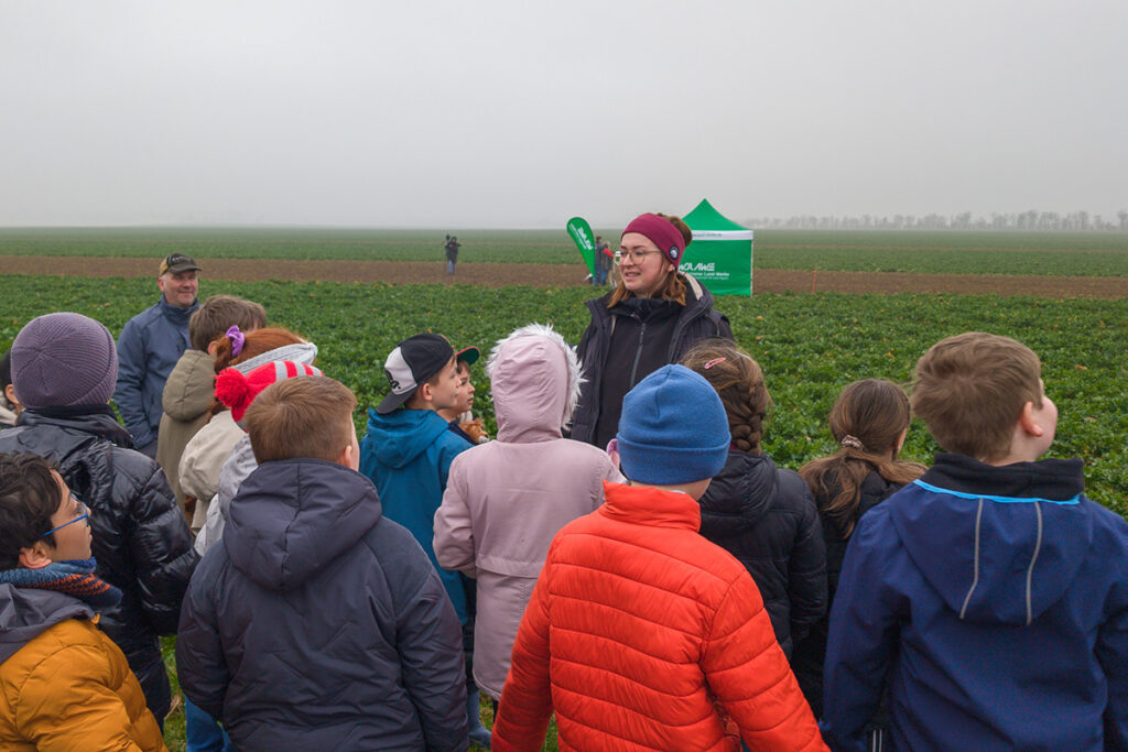 Stefanie Kleine begrüßt die Kinder Stefanie Kleine begrüßt die Schülerinnen und Schüler der Ringelnatz-Grundschule am Rand des Feldes