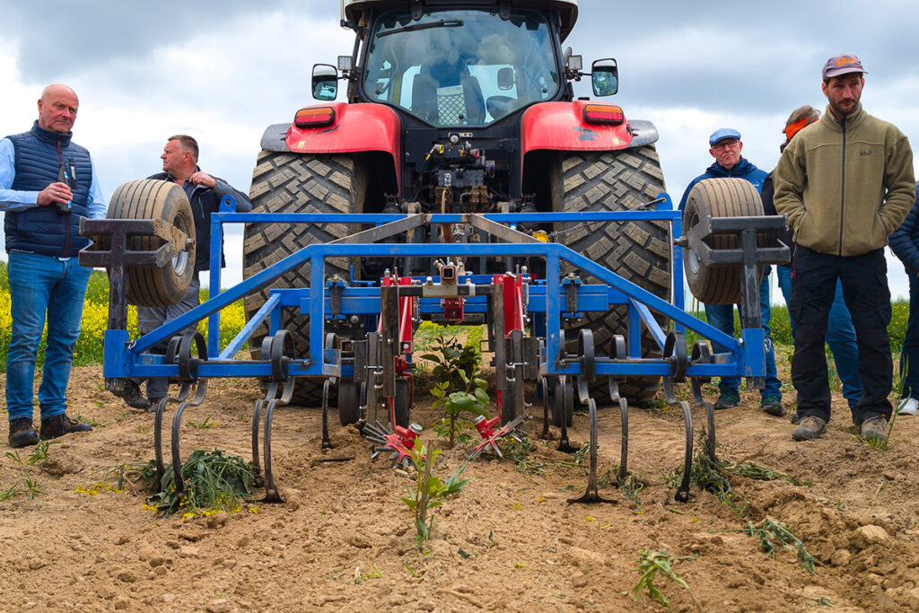 Traktor mit Vorrichtung Ein Traktor mit einer Vorrichtung zur Beseitigung von Pflanzen, die unmittelbar neben der Baumreihe wachsen